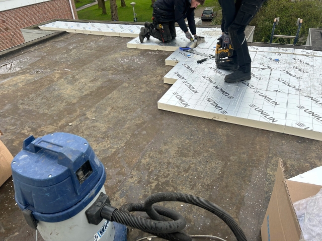 Dakdekkers van De Dakmannen brengen dakisolatie aan op een plat dak